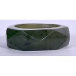 A CHINESE CARVED SPINACH JADE RING, facetted in form. 2.5 cm wide.
