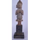 A NIGERIAN YORUBA WOODEN FERTILITY FIGURE, formed as a female squeezing her breasts. 32 cm high.