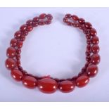 AN ART DECO CHERRY AMBER NECKLACE. 100 grams. 80 cm long, largest bead 2.75 cm wide.