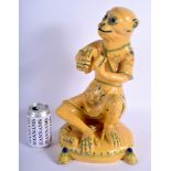 A LARGE EARLY 20TH CENTURY CONTINENTAL YELLOW GLAZED FAIENCE MONKEY modelled playing a tambourine.