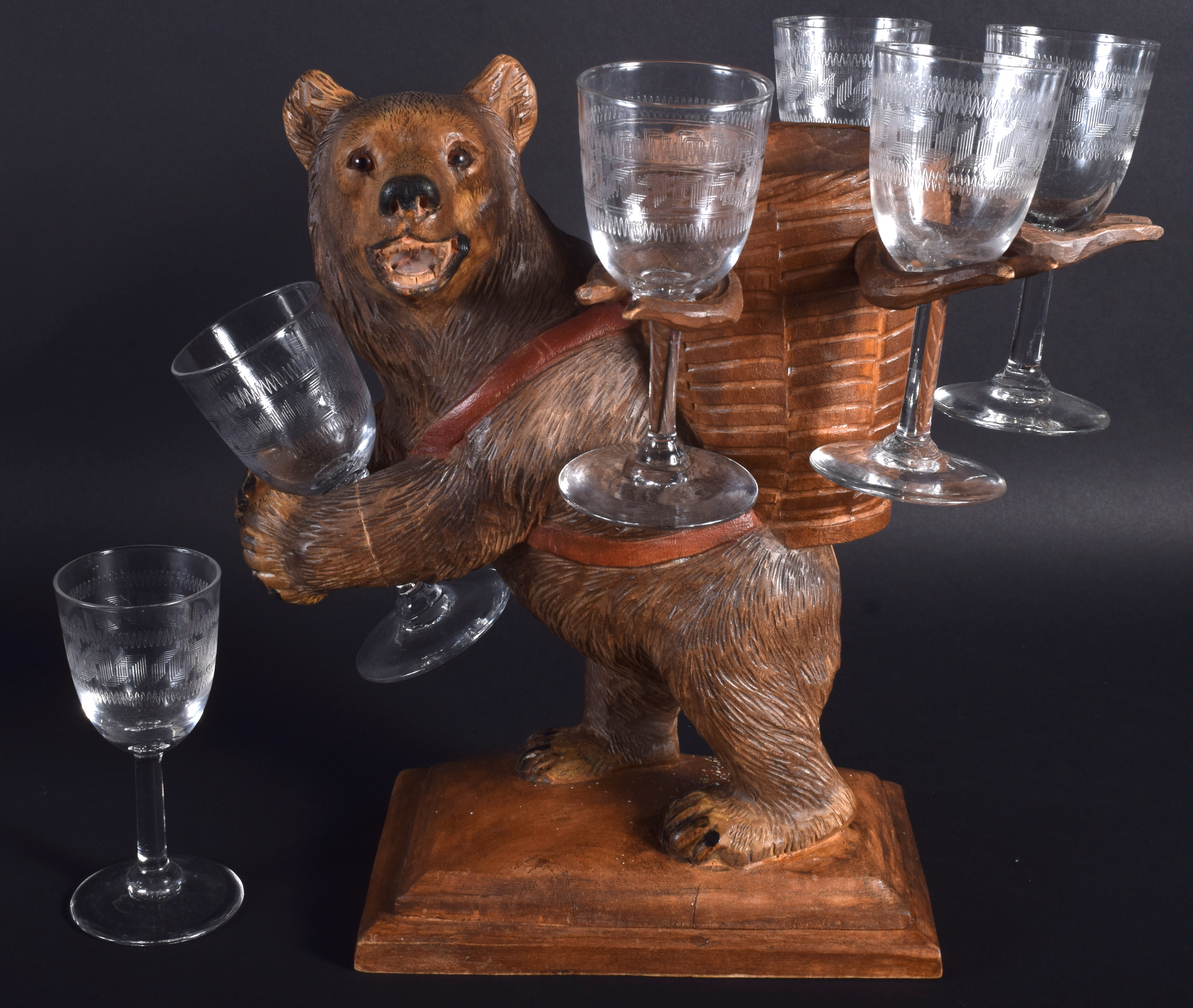 A 19TH CENTURY BAVARIAN BLACK FOREST ROAMING BEAR modelled holding six glasses. 28 cm x 32 cm.