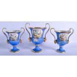 A SET OF THREE EARLY 19TH CENTURY DERBY TWIN HANDLED URNS painted with birds within landscapes. Lar