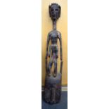 A LARGE AFRICAN CARVED LWALWA TYPE WOODEN MASK, formed with figural finial. 108 cm long.