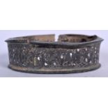 AN ISLAMIC SILVER AND YELLOW METAL INLAID BANGLE, decorated with script. 10.5 cm wide.