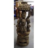 A LARGE CAMEROONIAN WOODEN TRIBAL FIGURE, formed as a central figure holding aloft a shell covered