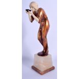 AN ART DECO STYLE IVORINE COLD PAINTED SPELTER FIGURE OF A FEMALE modelled peering into a bowl. 28