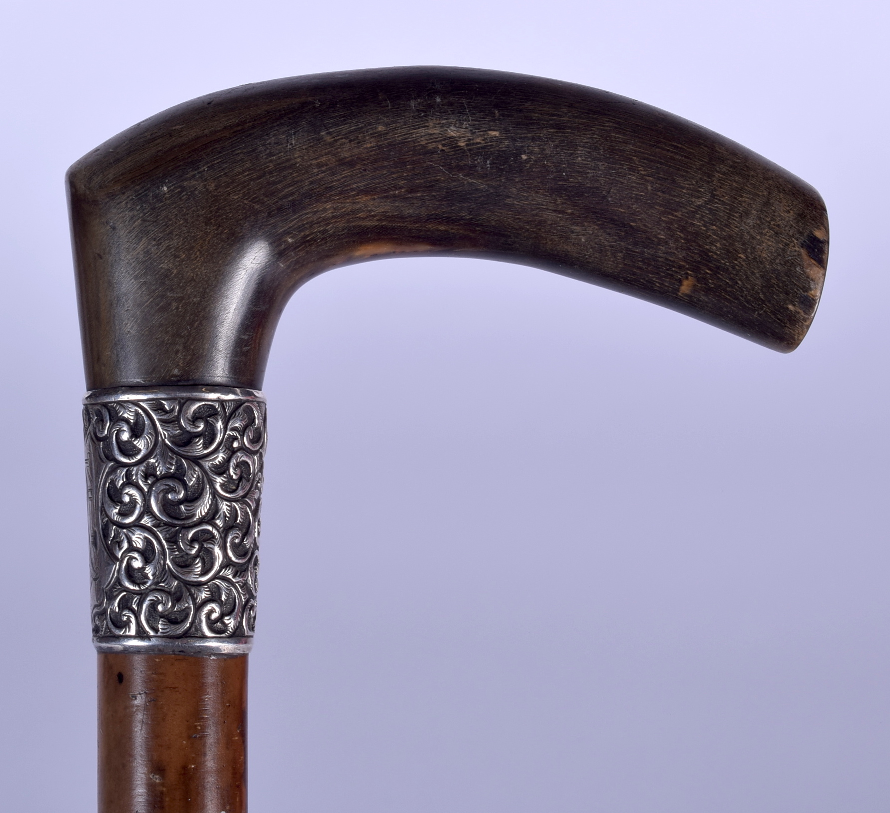 AN EARLY 20TH CENTURY RHINOCEROS HORN HANDLED WALKING STICK, formed with silver repousse collar. 89