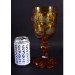 A 19TH CENTURY BOHEMIAN AMBER GLASS GOBLET decorated with buildings. 25 cm high.