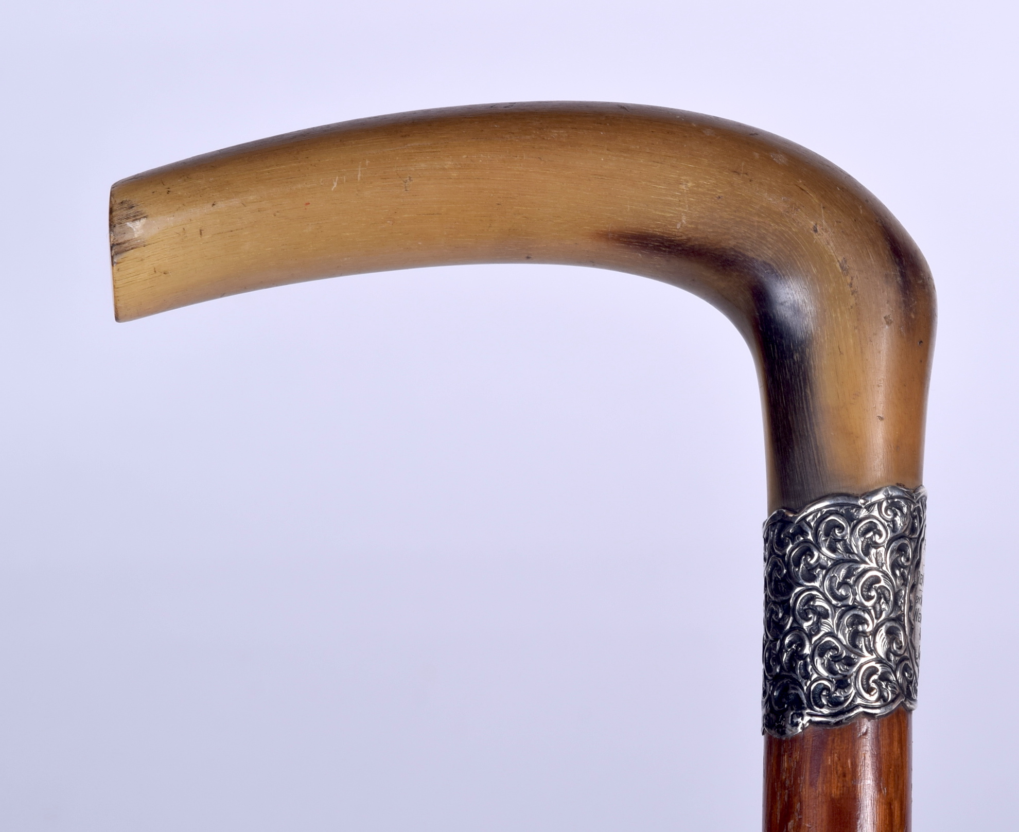 AN EARLY 20TH CENTURY RHINOCEROS HORN HANDLED WALKING STICK, formed with a silver repousse collar a