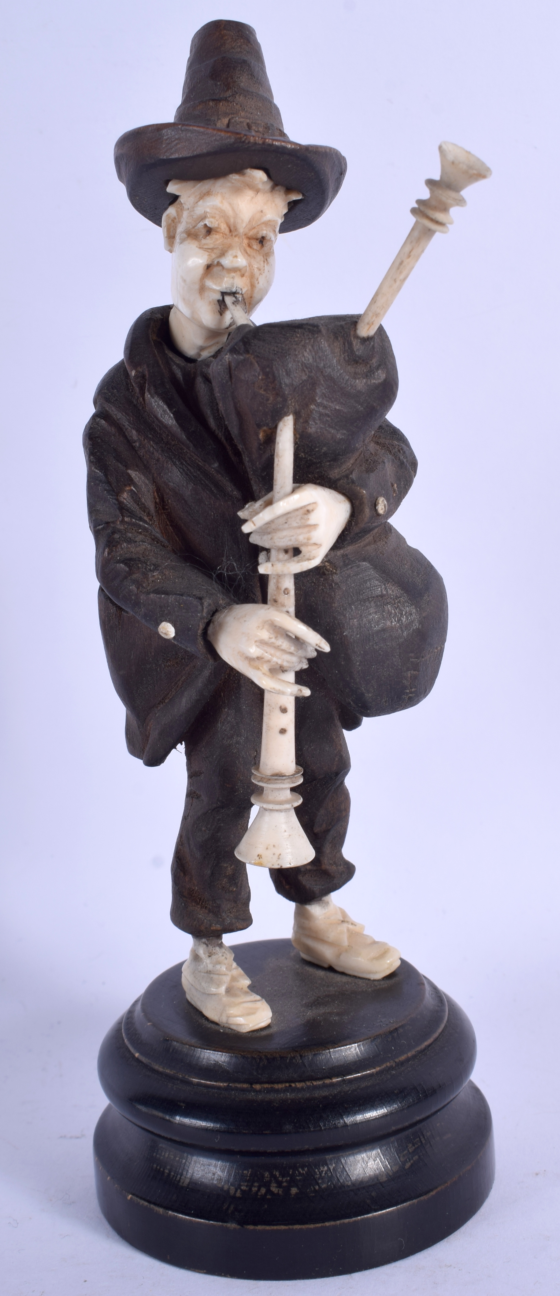 A 19TH CENTURY BAVARIAN CARVED WOOD BLACK FOREST MUSICIAN modelled playing bag pipes. 18 cm high.