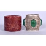 A CHINESE HARDSTONE ARCHERS RING, together with an apple jade inset white metal ring. (2)