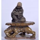 A CHINESE SOAPSTONE CARVED FIGURE OF BUDDHA, together with an olive glazed pottery stand. Total 17