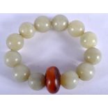 AN EARLY 20TH CENTURY CHINESE JADE SPHERICAL BEAD BRACELET, formed with a flattened amber coloured b