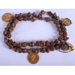 AN EARLY CONTINENTAL CARVED NUT WOOD NECKLACE with three attached yellow metal coins. 76 cm long.