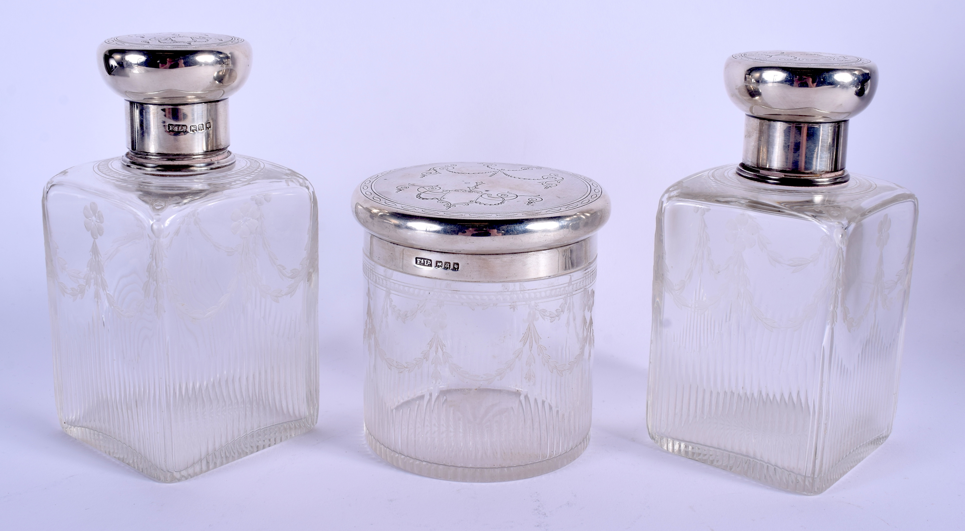 A SET OF THREE EDWARDIAN NEO CLASSICAL SILVER TOPPED BOTTLES. London 1916. Largest 16.5 cm high. (3)