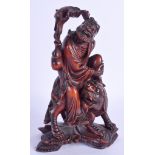 A 19TH CENTURY CHINESE CARVED WOOD FIGURE OF A BUDDHISTIC MALE modelled upon a beast. 18 cm x 11 cm.