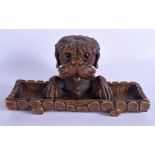 A 19TH CENTURY BAVARIAN BLACK FOREST DOGGY DESK STAND formed as an open pen tray with hidden inkwell