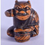 A 19TH CENTURY JAPANESE MEIJI PERIOD CARVED BOXWOOD NETSUKE modelled as a seated oni holding his che