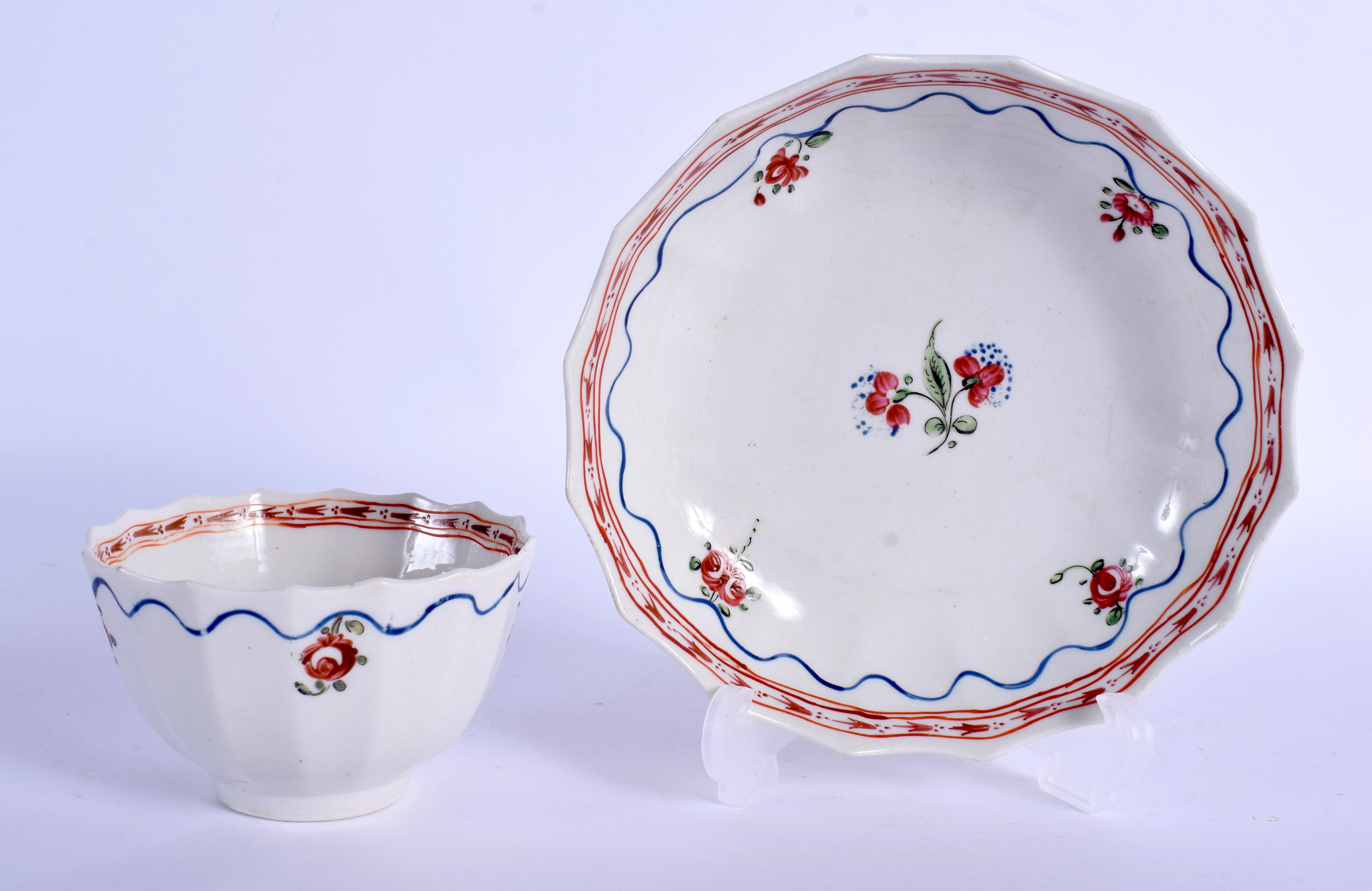 AN 18TH CENTURY LOWESTOFT TEABOWL AND SAUCER painted with central floral sprigs under an iron red bo