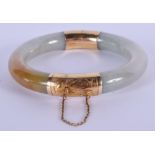 AN EARLY 20TH CENTURY CHINESE GOLD MOUNTED JADEITE BANGLE. 8.25 cm wide.