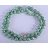 A 1950S CHINESE 14CT GOLD MOUNTED JADEITE NECKLACE. 70 cm long, bead 1.25 cm wide.