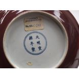 A CHINESE IRON RED PORCELAIN DISH incised with dragons, bearing Xuande marks to base. 20 cm diameter