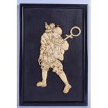 A 19TH CENTURY JAPANESE MEIJI PERIOD CARVED IVORY EBONISED PANEL modelled as a male holding a monkey