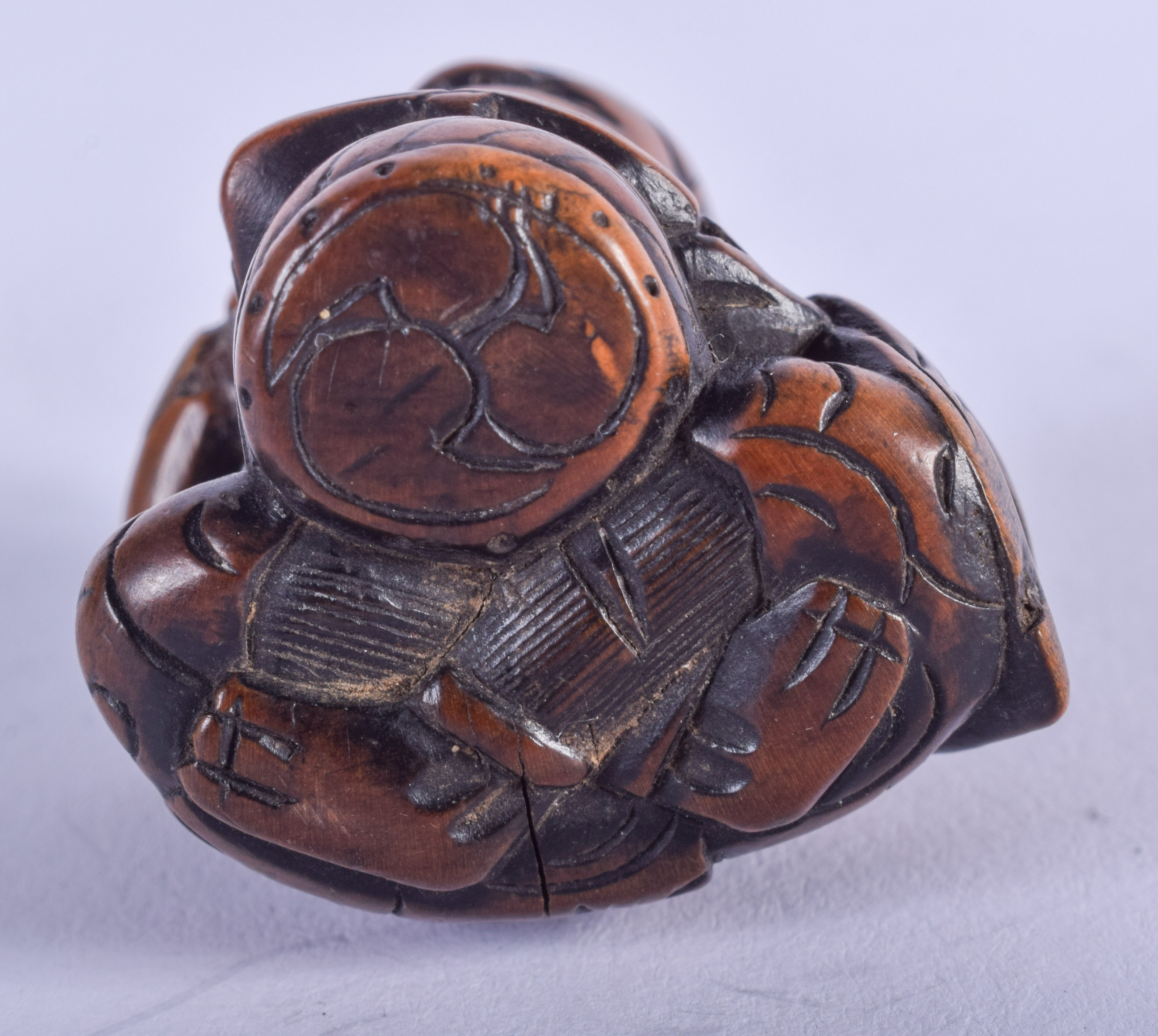 A 19TH CENTURY JAPANESE MEIJI PERIOD CARVED BOXWOOD NETSUKE modelled as a seated oni holding his che - Image 3 of 3