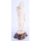A 19TH CENTURY JAPANESE MEIJI PERIOD CARVED IVORY OKIMONO modelled as a female holding a flower. Ivo