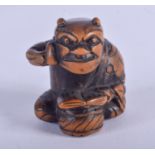 A 19TH CENTURY JAPANESE MEIJI PERIOD CARVED BOXWOOD NETSUKE modelled as a seated oni holding his che