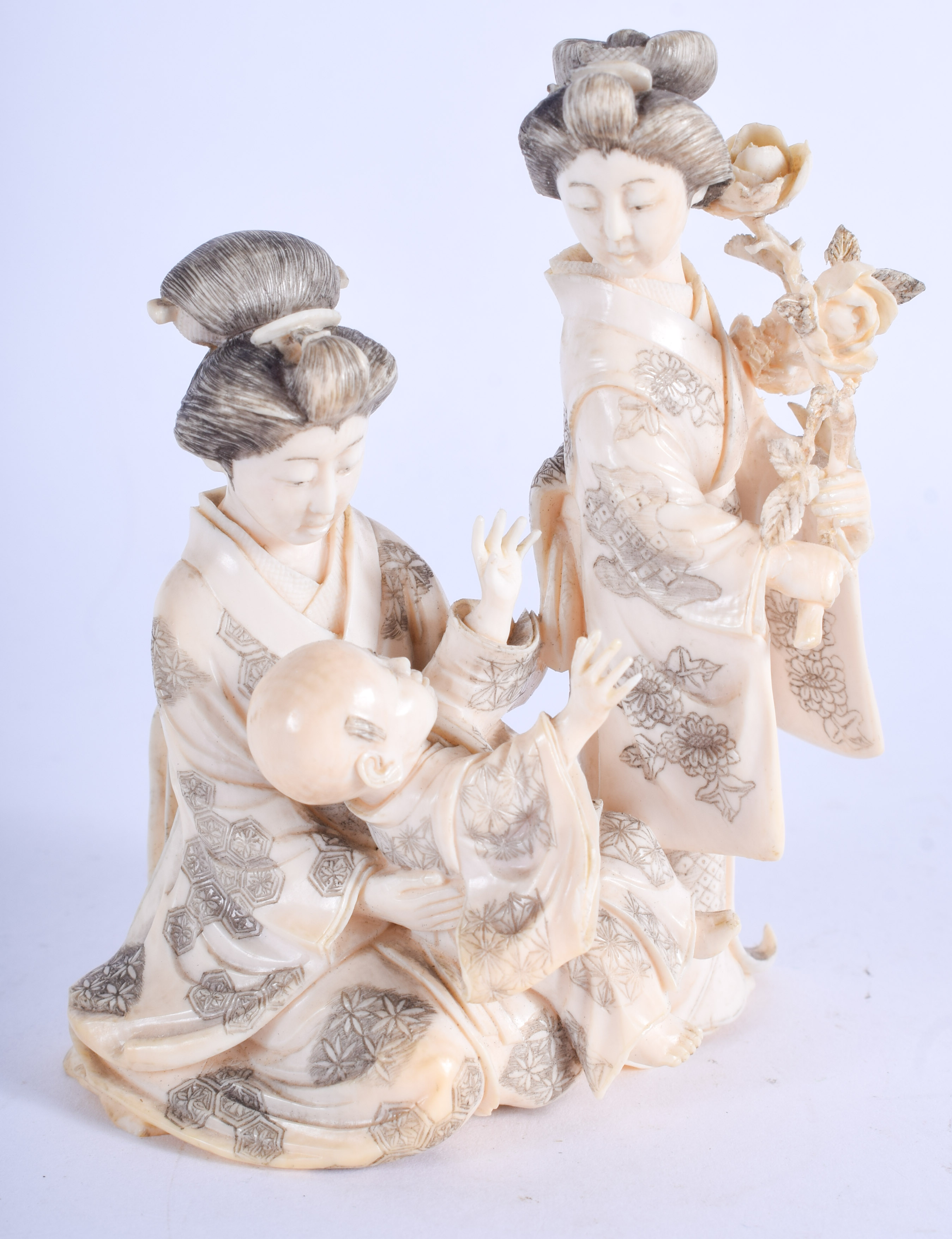 A FINE 19TH CENTURY JAPANESE MEIJI PERIOD CARVED IVORY OKIMONO modelled with geisha holding foliage.