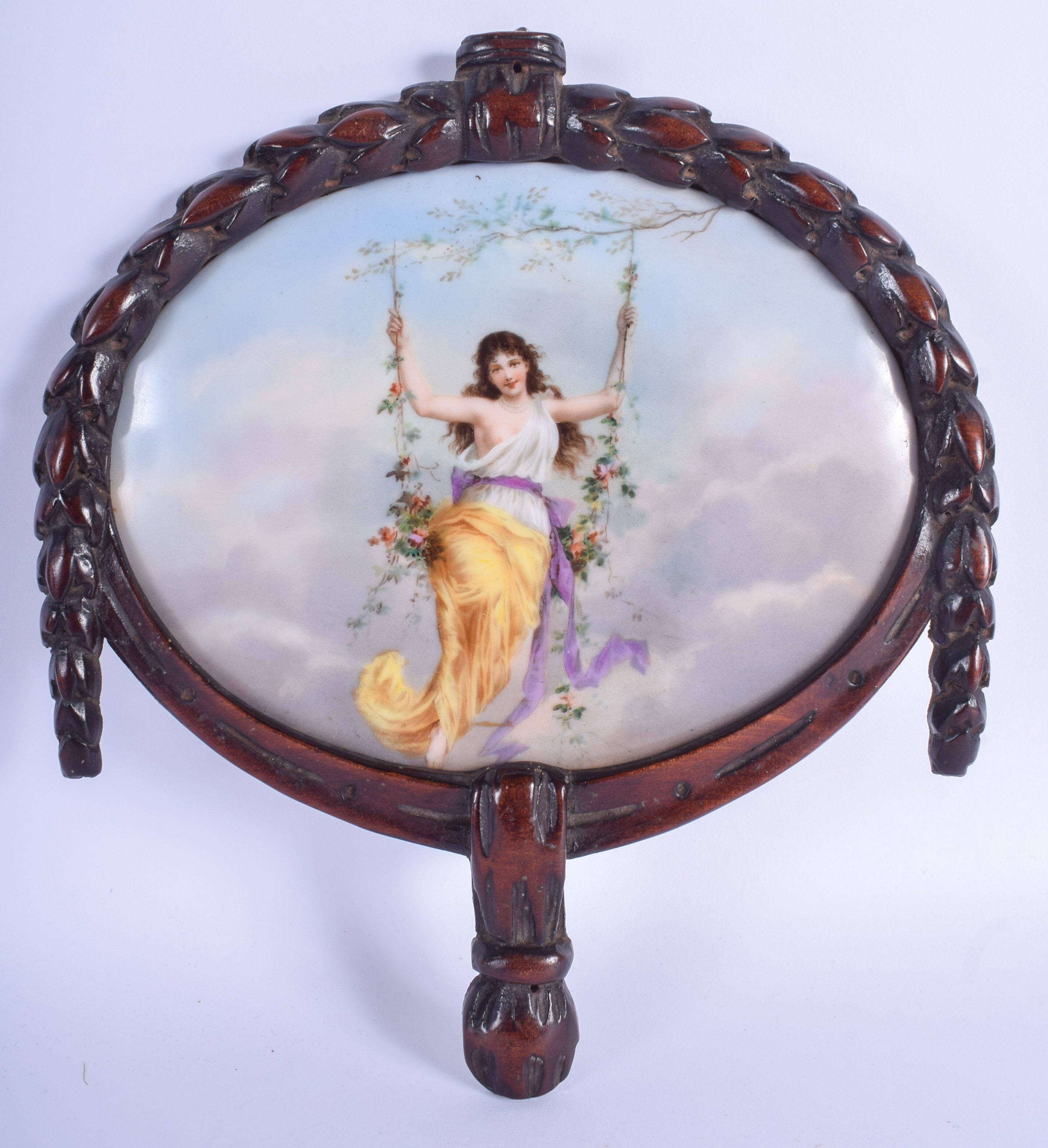 AN EARLY 20TH CENTURY EUROPEAN FAN SHAPED PORCELAIN PLAQUE painted with a female upon a floral swing