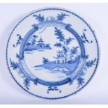 A LARGE 18TH CENTURY DELFT BLUE AND WHITE TIN GLAZED CHARGER painted with landscapes. 33 cm diameter