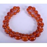 A 1930S AMBER BEAD NECKLACE. 68 cm long, largest bead 2.25 cm wide.