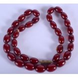 A 1920S CHERRY AMBER NECKLACE. 21.5 grams. 44 cm long, largest bead 1.25 cm wide.