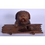 A 19TH CENTURY BAVARIAN BLACK FOREST CARVED WOOD INKWELL modelled as a recumbent hound beside an ope