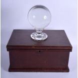AN ANTIQUE CRYSTAL BALL ON STAND within a mahogany box. Box 34 cm wide, ball 11 cm diameter. (2)