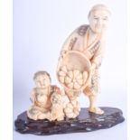 A 19TH CENTURY JAPANESE MEIIJI PERIOD CARVED IVORY OKIMONO modelled as a male and child picking frui