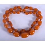 AN EARLY 20TH CENTURY MIDDLE EASTERN CARVED AMBER NECKLACE of graduated form.77 grams. 72 cm long, l