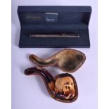 A 19TH CENTURY CARVED MEERSCHAUM SKULL PIPE together with a silver dupont pen. Pipe 12 cm wide. (2)