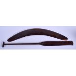 A TRIBAL AUSTRALIAN CARVED WOOD BOOMERANG together with a palm wood paddle. Largest 62 cm long. (2)