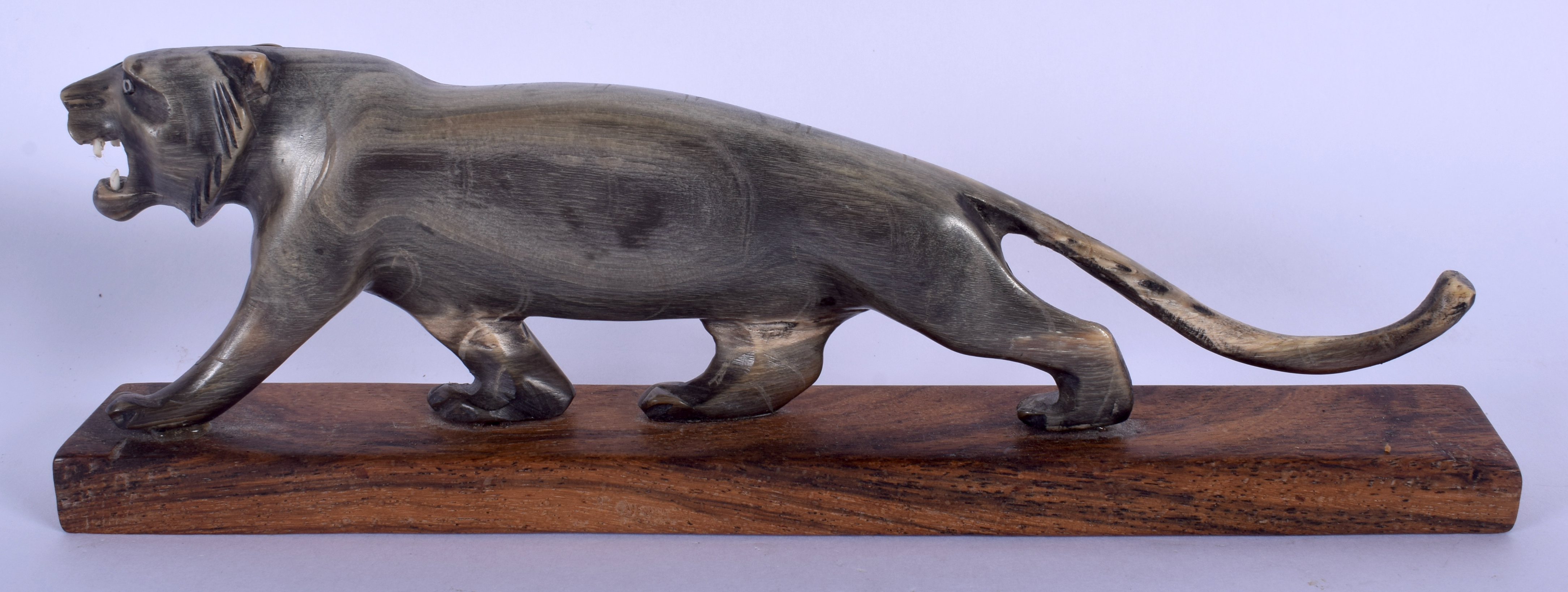 A 19TH CENTURY MIDDLE EASTERN CARVED RHINOCEROS HORN TIGER upon a wooden plinth. Figure 20 cm wide.