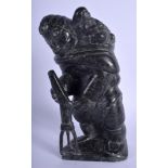 A NORTH AMERICAN CARVED INUIT SOAPSTONE FIGURE OF A HUNTER modelled with a child upon there back. 27