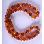 A 1930S ORANGE AND BUTTERSCOTCH AMBER NECKLACE of uni-form. 35 grams. 48 cm long, each bead 0.5 cm w