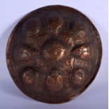 AN UNUSUAL 19TH CENTURY INDIAN TIBETAN COPPER SHIELD decorated with mask heads and figures. 32 cm di