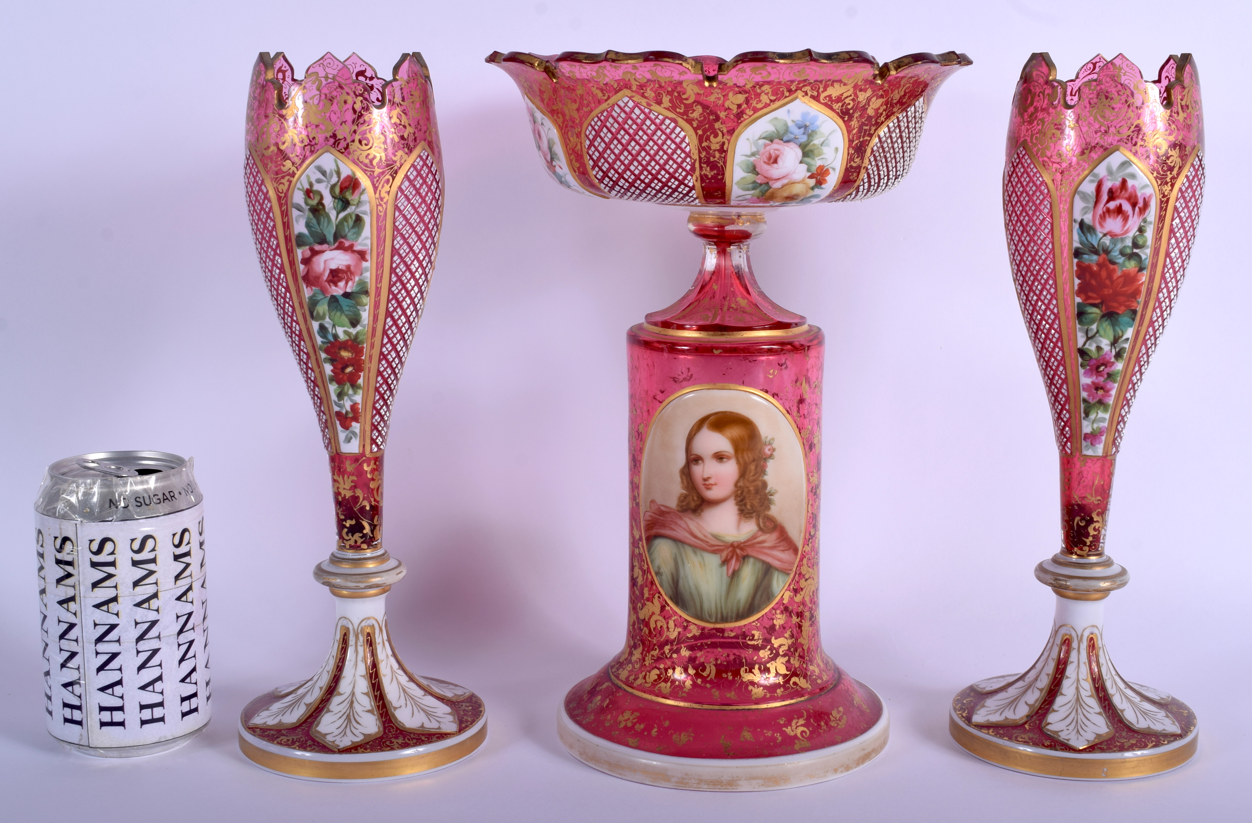 A 19TH CENTURY BOHEMIAN CRANBERRY GLASS GARNITURE enamelled with a portrait of a female, the vases o