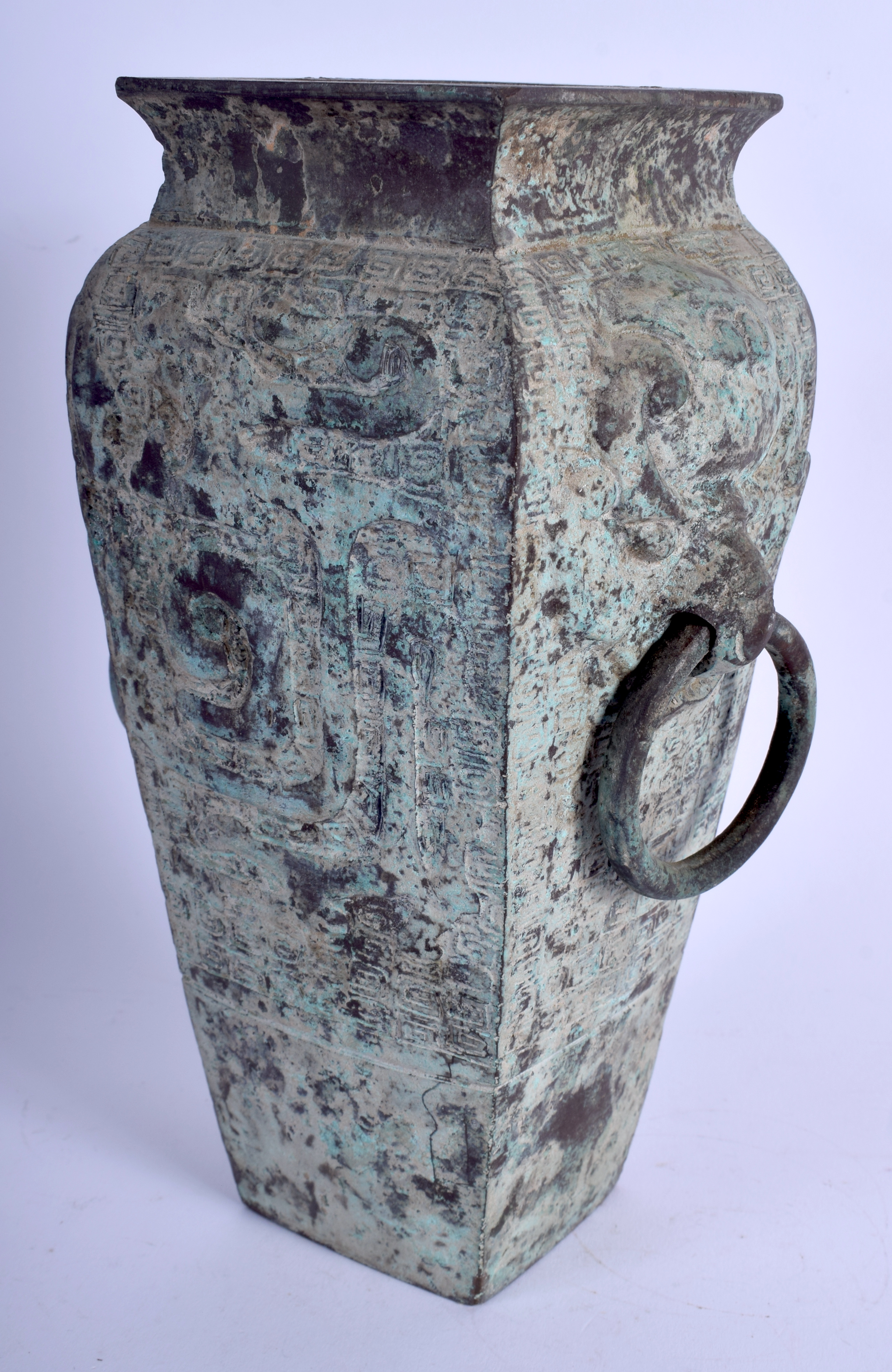 A 1930S CHINESE BRONZE SQUARE FORM VASE of archaic form, decorated with mask heads. 23 cm x 9 cm.