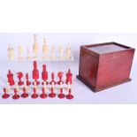 A 19TH CENTURY CONTINENTAL CARVED AND STAINED BONE CHESS SET within a sliding mahogany case. Largest