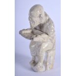 AN EARLY CHINESE FIGURE OF A SEATED MONK Ming, modelled holding a small offering table. 12 cm high.