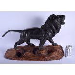A 19TH CENTURY JAPANESE MEIJI PERIOD BRONZE OKIMONO modelled as a roaming lion upon a wooden plinth